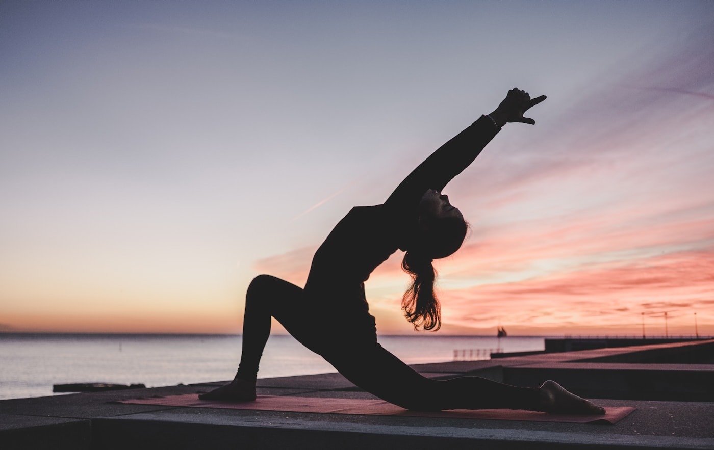 A person doing yoga beside the water